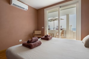 A bedroom with a bed, a chair, and a view of a balcony with outdoor furniture. - Villa 'Dimora Egle' with Private Terrace, Wi-Fi and Air Conditioning (Quartu Sant'Elena)