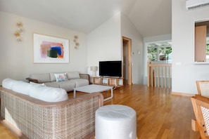 A living room with a sofa, a television, and a dining area with a table and chairs.