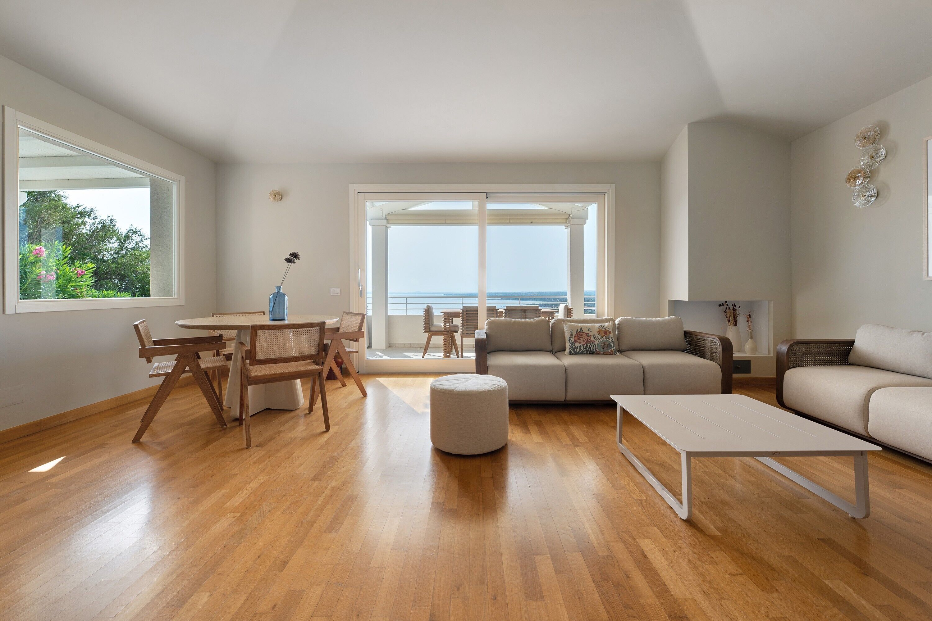 A modern living room with a wooden floor, a sofa, a coffee table, and a dining area with chairs and a table.