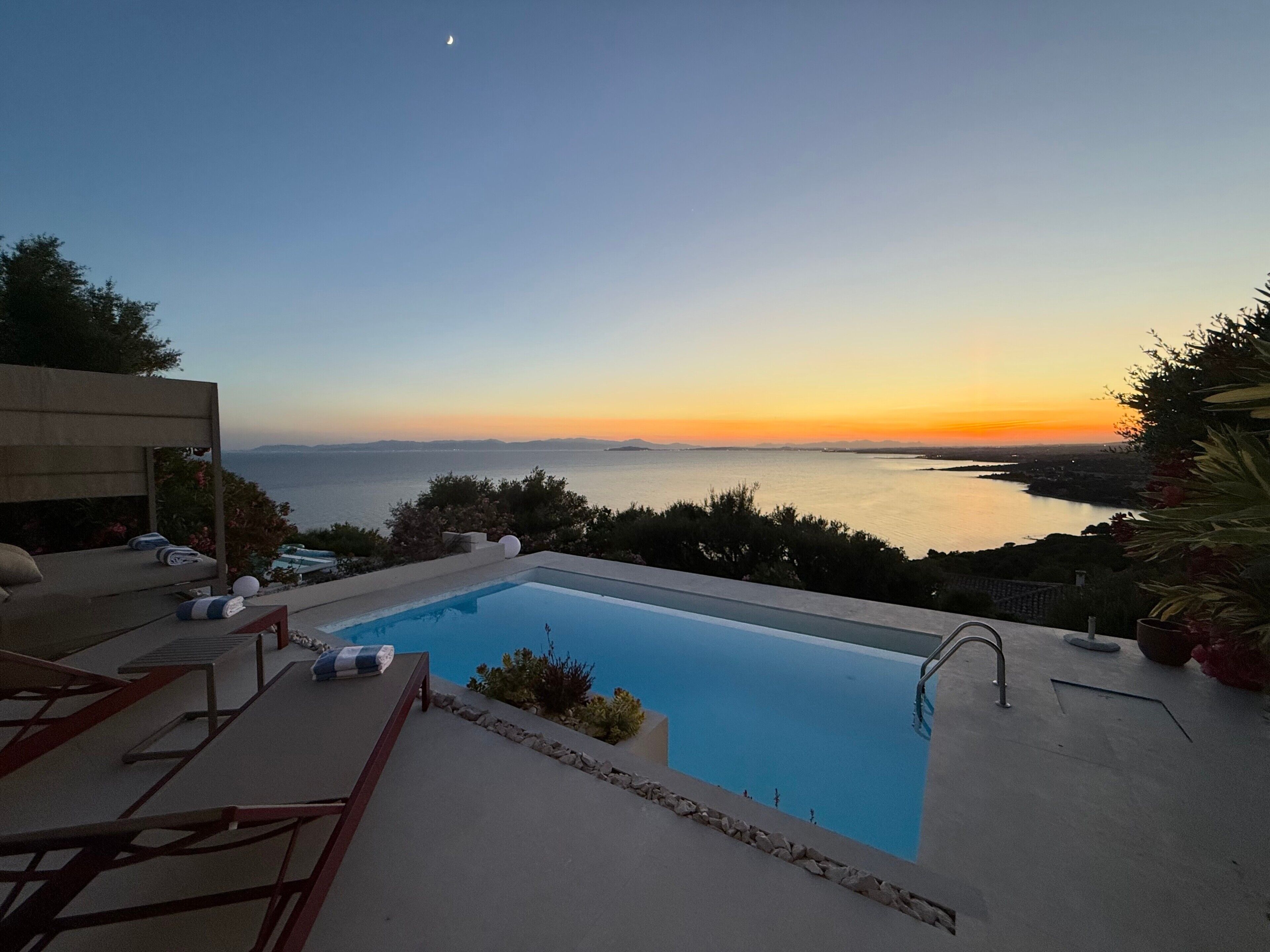 A swimming pool with a view of the sea and a sunset.