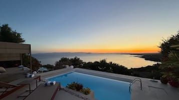 A swimming pool with a view of the sea and a sunset.