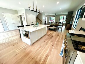 A spacious kitchen with a central island, wooden flooring, and modern appliances. - Bolton Creekside Condo - Walk to lake, beaches, marinas, restaurants, shops (Bolton Landing)
