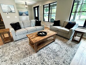 Un salon avec deux canapés gris, une table basse en bois et un tapis à motifs.