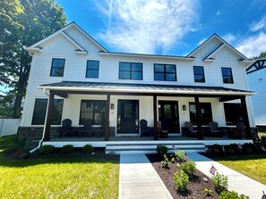 A two-story house with a covered porch and a front yard. - Bolton Creekside Condo - Walk to lake, beaches, marinas, restaurants, shops (Bolton Landing)