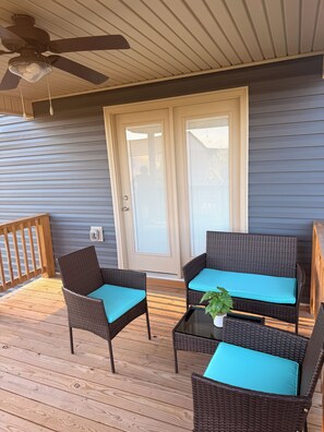 A covered porch with wicker furniture, a ceiling fan, and a door with a window.