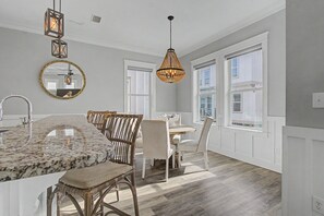Uma cozinha moderna com ilha de mármore, cadeiras de vime e iluminação pendente.