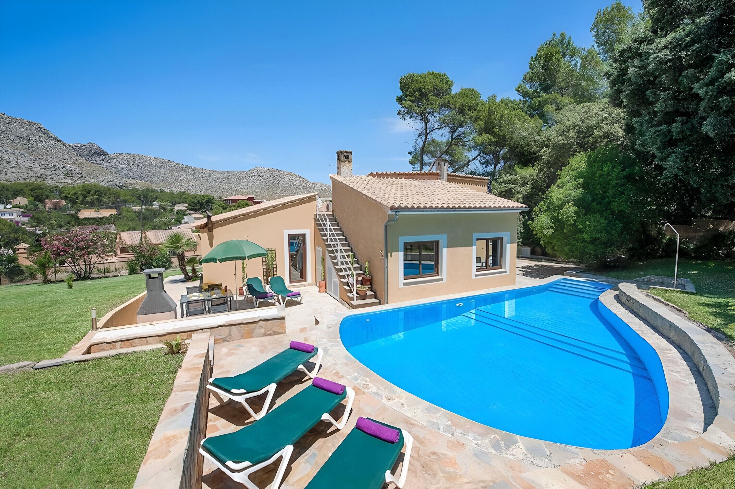 A swimming pool with lounge chairs, a patio area, and a small building with a staircase.