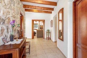 A hallway with stone walls, wooden beams, a wooden bench, a table with a lace tablecloth, and a mirror on the wall. - Villa "Alexandria" with Mountain View, Pool, A/C, Terrace & Garden (Cala Sant Vicenç)