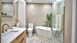 Ein modernes Badezimmer mit Marmorwaschbecken, Toilette und freistehender Badewanne.