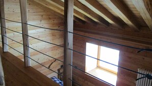 A wooden interior with a sloped ceiling, a window, and a visible staircase.