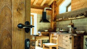 A wooden interior with a door, a kitchen area with a stove, and a dining table.