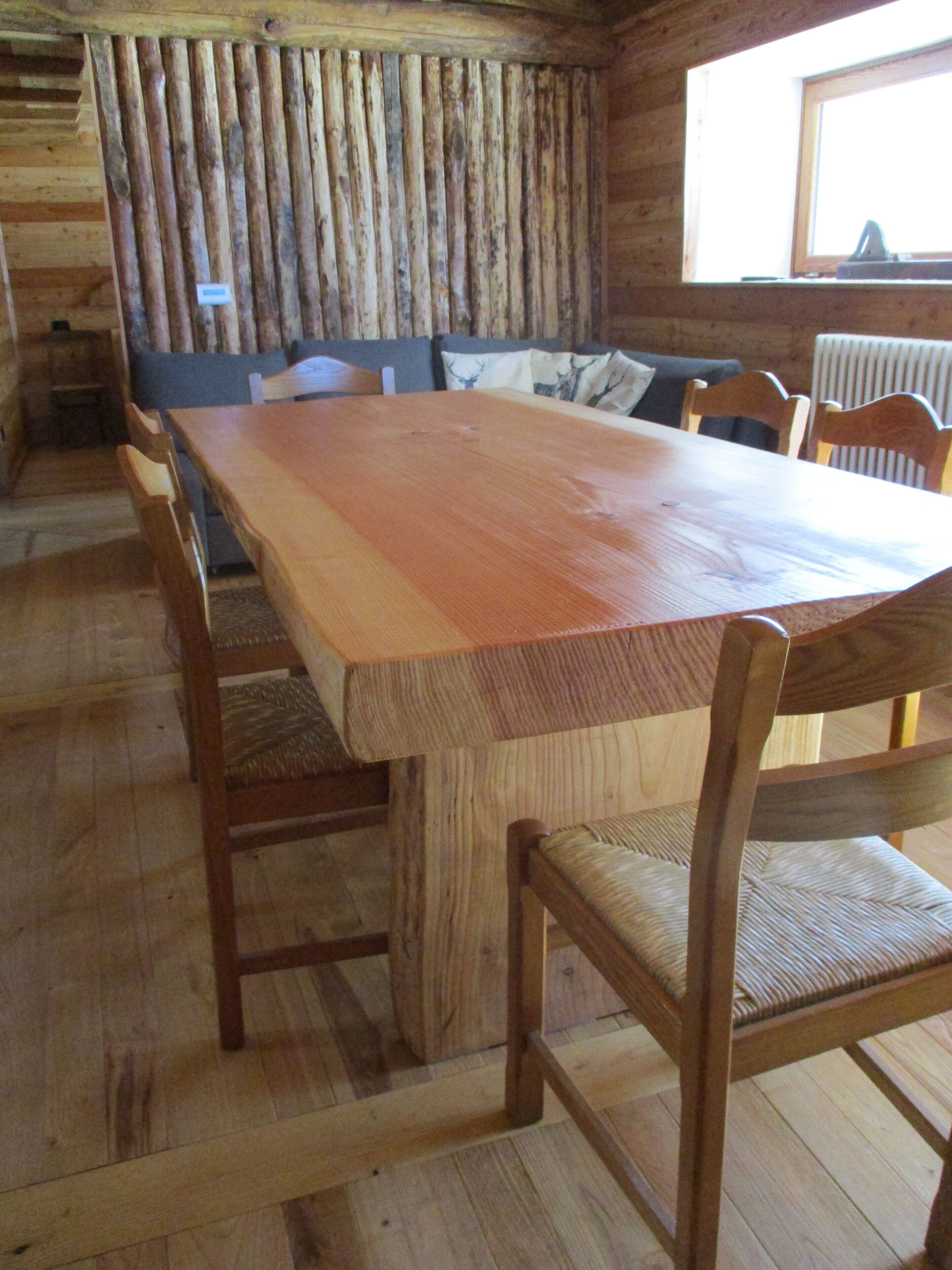 Un tavolo da pranzo in legno con sedie, una panca e una finestra con persiane.