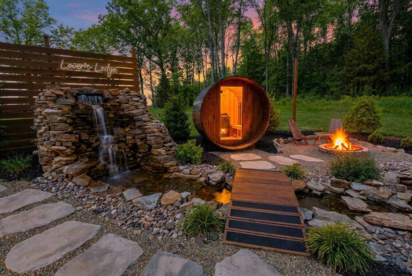 Een rustieke lodge met een stenen waterval, een houten vatstructuur, een vuurkuil en een pad van stenen.