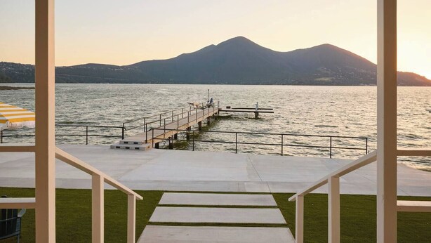 Une terrasse qui mène à une jetée s’avançant dans un lac, avec des montagnes en arrière-plan.