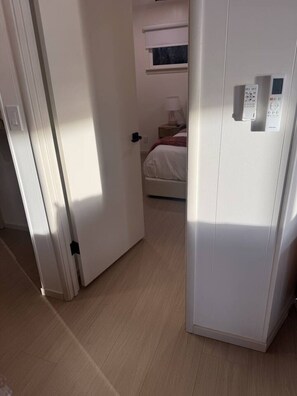 Ein Zimmer mit Bett, Nachttisch, Fenster und Tür.