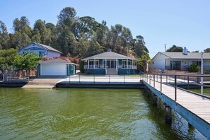 Ein Wohnhaus am Wasser mit Anlegesteg, überdachter Veranda und Garage.