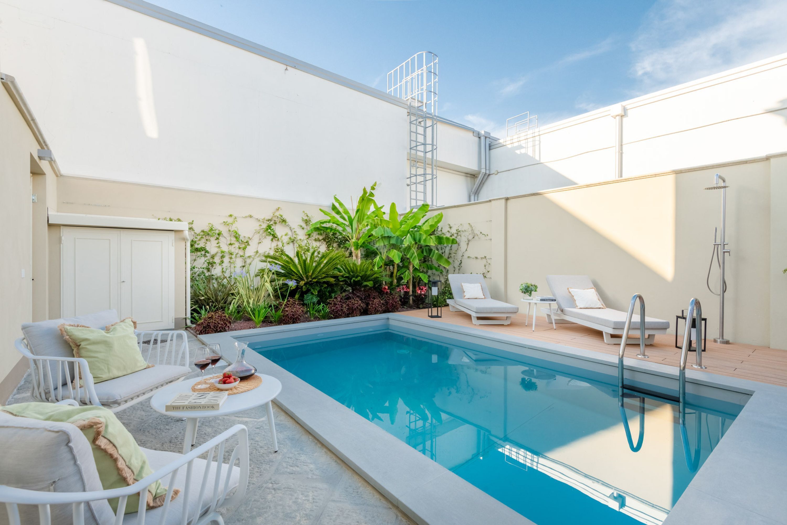Un espace piscine avec des chaises longues, une table avec un livre et un escalier menant au toit.