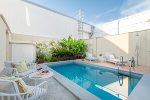 A pool area with lounge chairs, a table with a book, and a ladder leading to a roof. - The Secret Garden Cottage (Lucca)