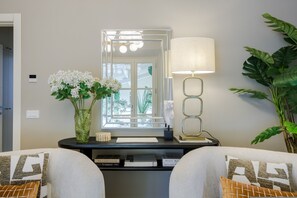 Ein Zimmer mit Spiegel, Lampe, Blumen in einer Vase und einer Pflanze.