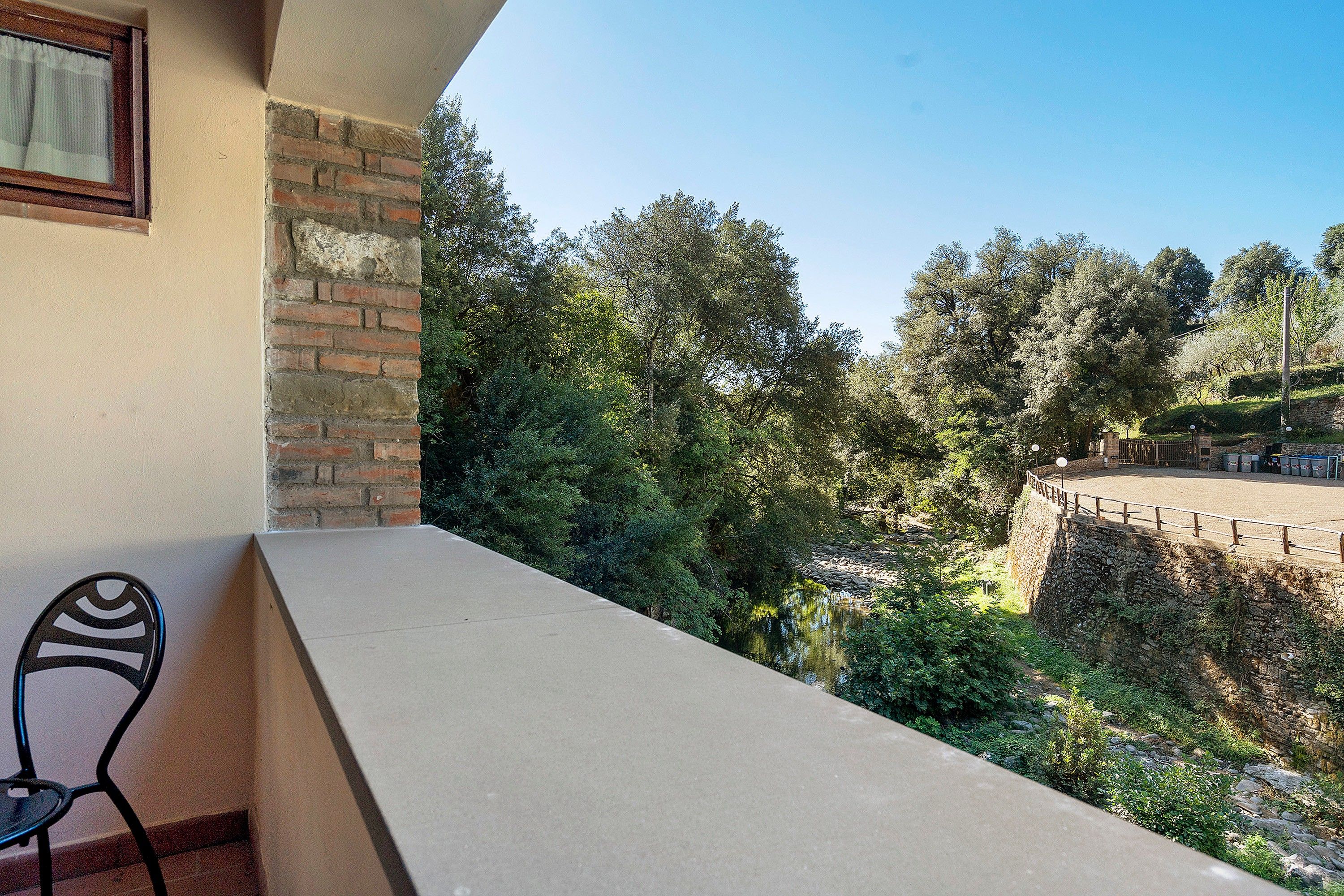 A balcony with a view of a stone wall and trees.