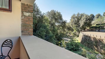 A balcony with a view of a stone wall and trees.