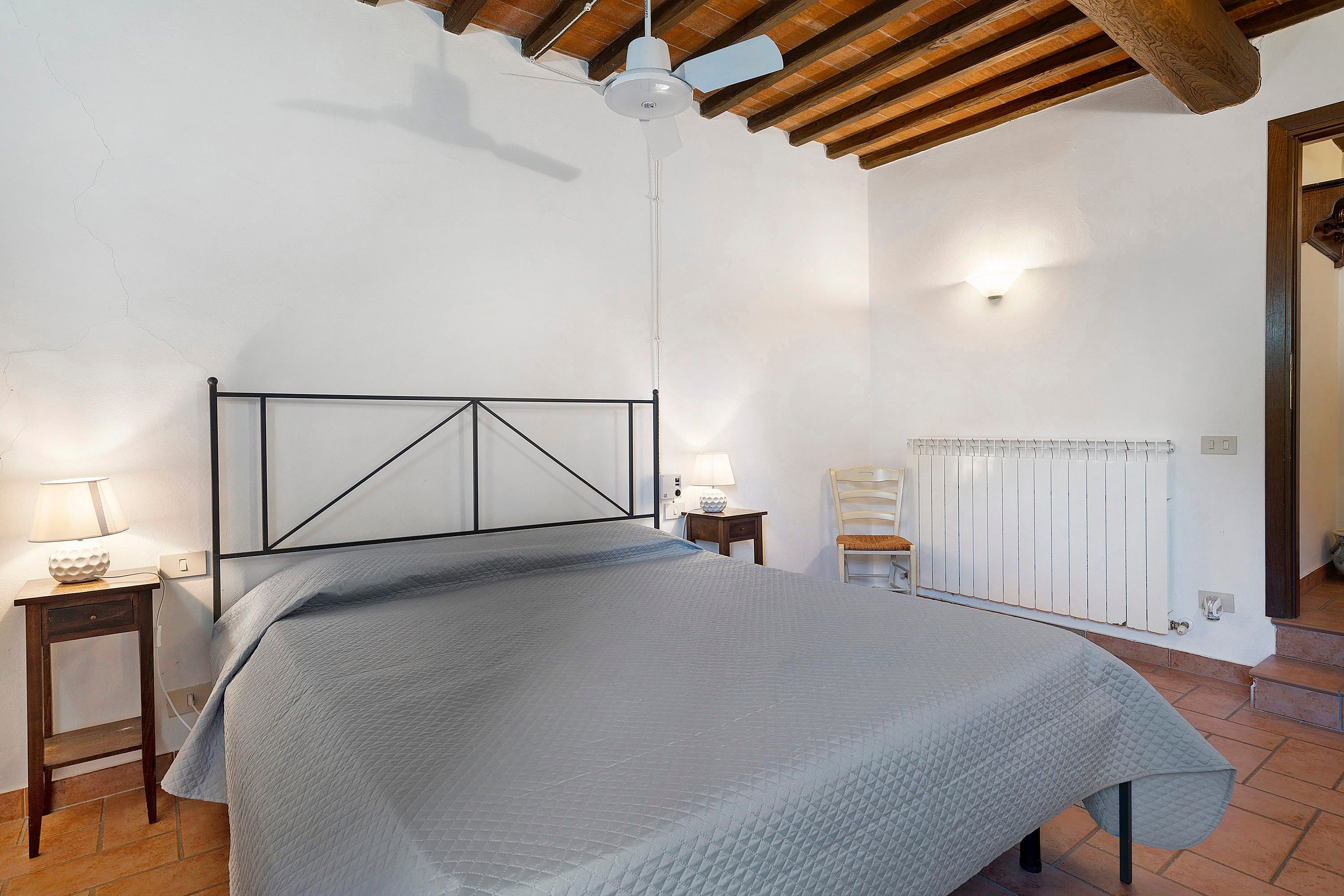 Ein Schlafzimmer mit einem Bett, einem Nachttisch, einer Lampe, einem Sessel und einer Heizung.