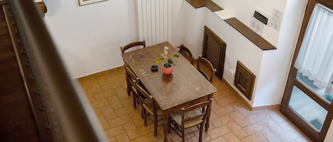 Uma área de refeições com mesa de madeira, cadeiras e um vaso de planta.