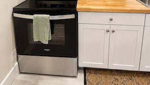A compact kitchen with a microwave, stove, toaster, and a coffee maker.