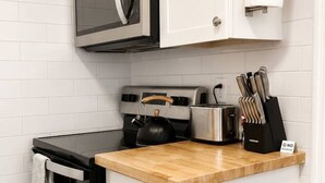 Uma cozinha compacta com micro-ondas, torradeira, chaleira e conjunto de facas na bancada.