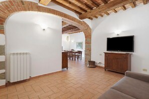 A spacious living area with a TV, a fireplace, and a dining area in the background. - Apartment 7 with Terrace - La Ferriera Residence with Pool (Loro Ciuffenna)