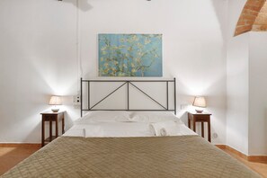 Ein Schlafzimmer mit einem Bett, zwei Nachttischen, einem Wandbild und einem Fliesenboden.