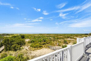 A coastal landscape with a white railing, sandy beach, and dense vegetation. - Stunning Oceanfront Home, Guest Cards & Golf Cart (Fripp Island)