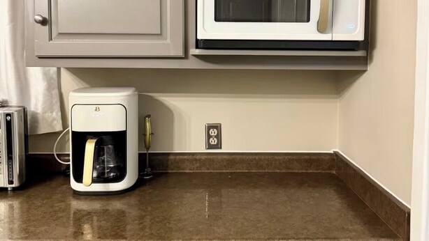 Een keuken met een magnetron, koffiezetapparaat en twee lades.
