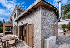 Una casa de piedra con balcón, una mesa y sillas afuera y una chimenea.