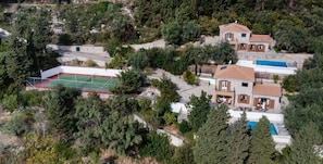 Una propiedad residencial con cancha de tenis, piscina y un camino de piedra.