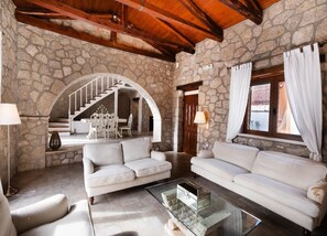 A spacious living area with stone walls, a staircase, and two sofas. - Villa Galatia - Three Bedroom Villa, Sleeps 6 (Perigiali)