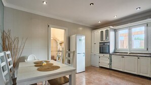 A modern kitchen with white cabinetry, a built-in oven, and a window overlooking the backyard. - Villa Casa Martin - Three Bedroom Villa, Sleeps 6 (Portocolom)