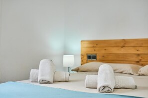 A hotel room with a wooden headboard, a bed with white linens, and a bedside lamp. - Villa Casa Martin - Three Bedroom Villa, Sleeps 6 (Portocolom)