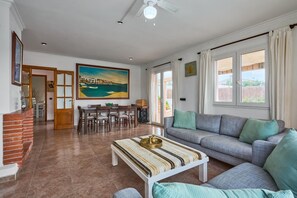 Ein großzügiger Wohnbereich mit einer Couch, einem Esstisch mit Stühlen, einem Kamin und einem großen Gemälde an der Wand.