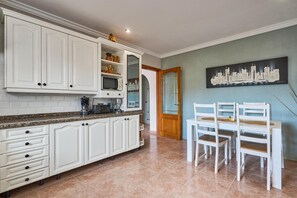 Eine Küche mit weißen Schränken, einer Granit-Arbeitsplatte und einem Essbereich mit weißen Stühlen und einem Tisch.