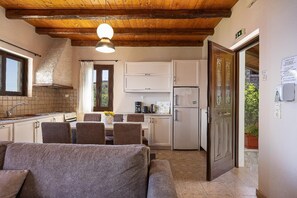A compact kitchen with a dining area, wooden ceiling, and a door leading outside. - Villa Forteza - Three Bedroom Villa, Sleeps 6 (Kalami)