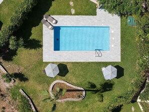 An aerial view of a rectangular swimming pool with two lounge chairs and two umbrellas on a well-maintained lawn. - Villa Forteza - Three Bedroom Villa, Sleeps 6 (Kalami)