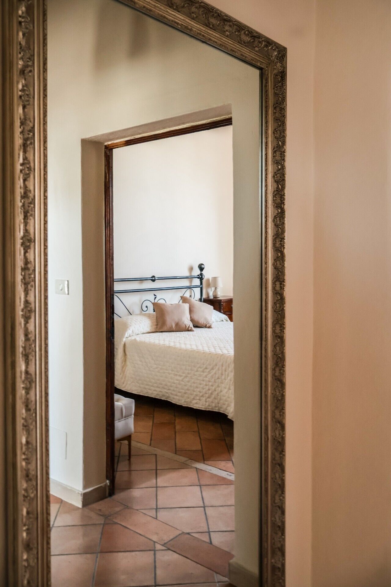Een slaapkamer met een bed, kussens, een nachtkastje en een bedtafel.