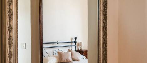 Een slaapkamer met een bed, kussens, een nachtkastje en een bedtafel.