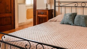 A bedroom with a bed, a nightstand, a lamp, and a wooden door. - La Casa sul Corso - In the Heart of Foiano della Chiana (Foiano della Chiana)