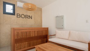 A room with a wooden headboard, a sofa, a wooden table, a wall-mounted air conditioner, a window, and a wall-mounted mirror. - 2-bedroom with Lagoon and Pool View (Bavaro)