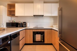Eine moderne Küche mit Holzschränken, einem Einbauofen, einem Geschirrspüler und einem Kühlschrank.