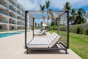 Ein moderner Poolbereich im Freien mit Liegestühlen und einer Pergola.