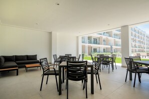 Ein stilvoller Innenbereich mit Essbereich, einer Couch und Stühlen, großen Fenstern und Blick auf ein Gebäude.