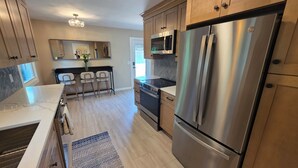 A modern kitchen with stainless steel appliances, wooden cabinets, and a marble countertop. - Spacious 5-bedroom house in Bloomington (Minneapolis)